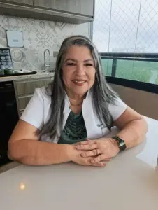 Geisa Drummond sentada à mesa, sorrindo